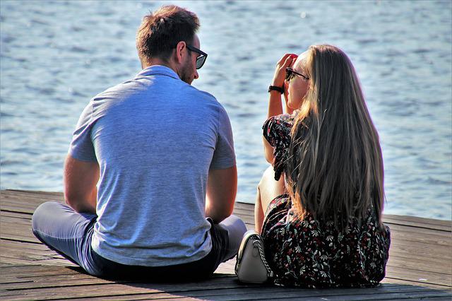 A couple speaking while sitting on a dock