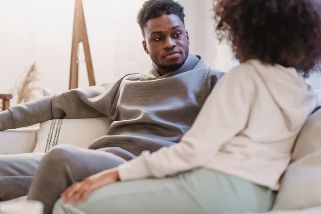 A couple sitting and talking on a couch