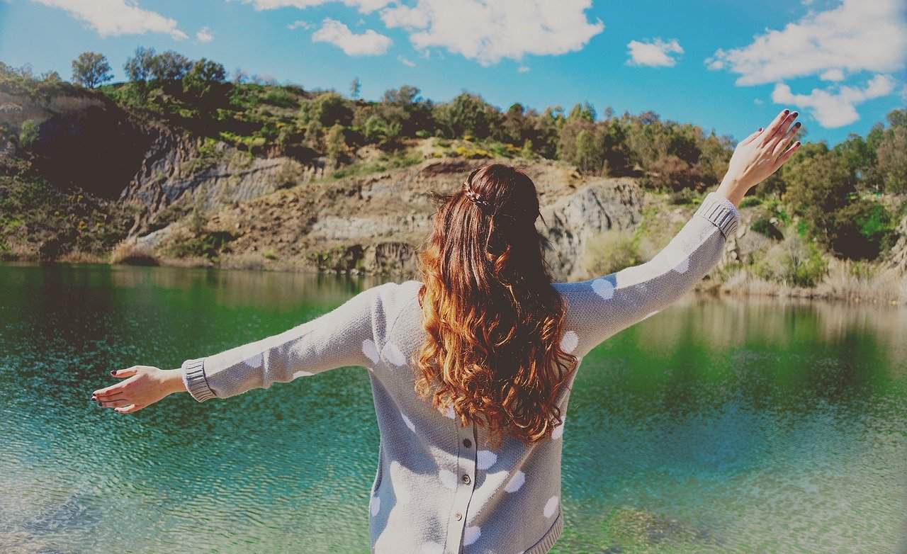 woman in power pose near lake